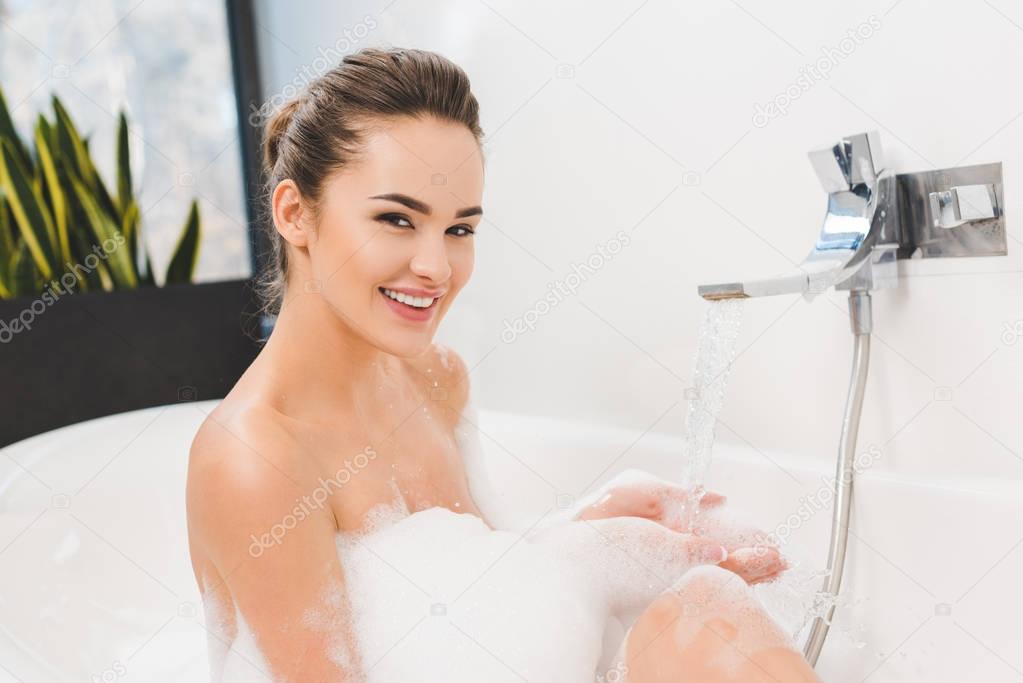 smiling young woman taking bath at home
