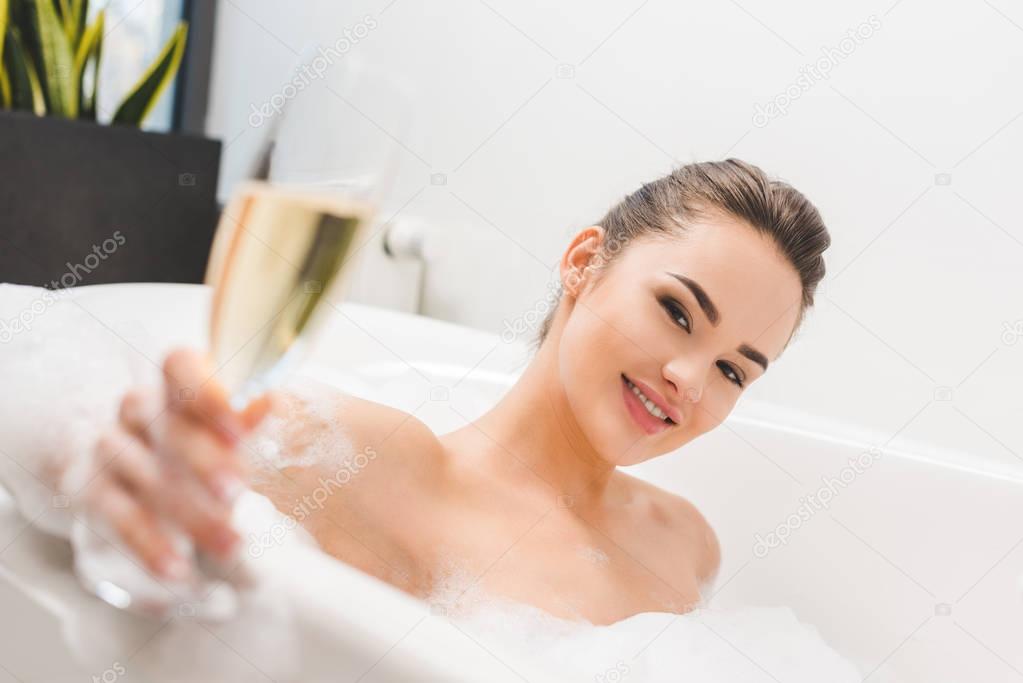 selective focus of beautiful woman with glass of champagne taking bath