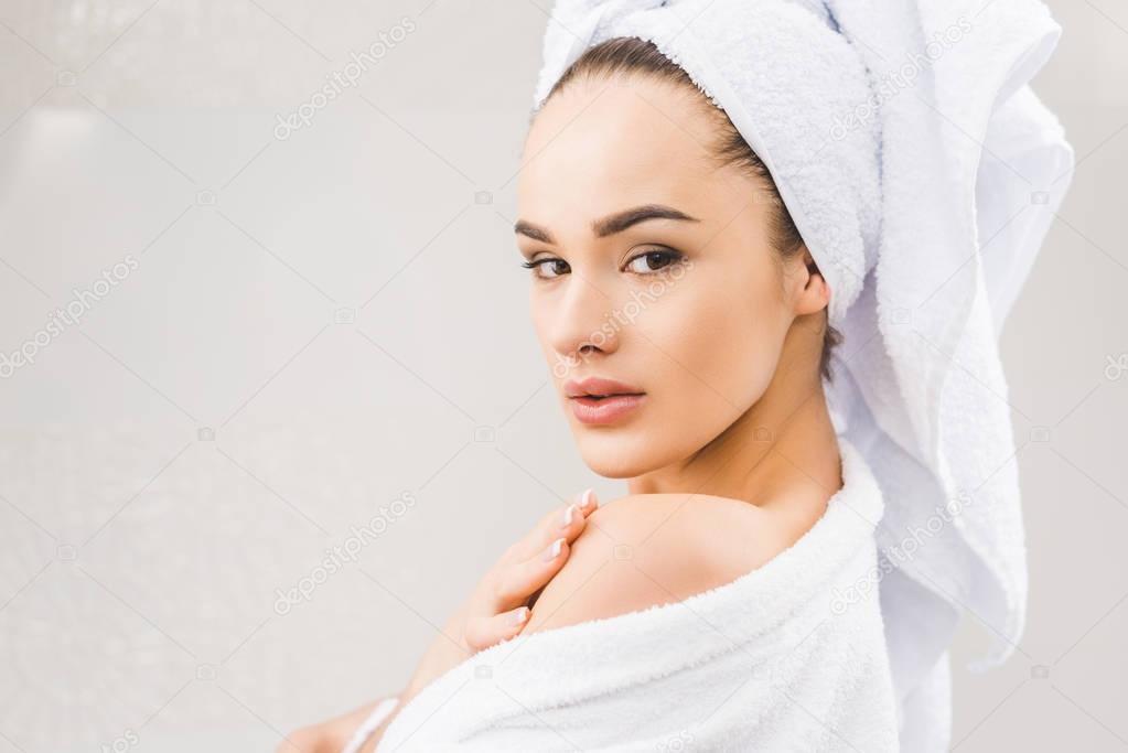 side view of beautiful young woman in bathrobe with towel on head at home
