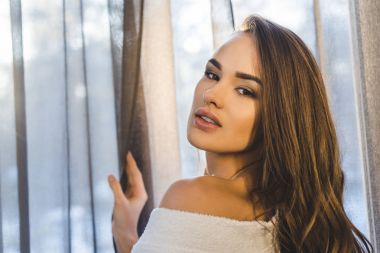 evde kameraya bakarak bornoz çekici genç kadın