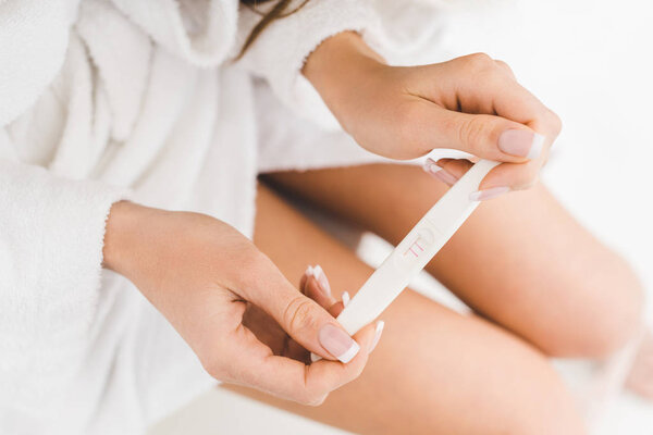 partial view of woman holding pregnancy test in hands