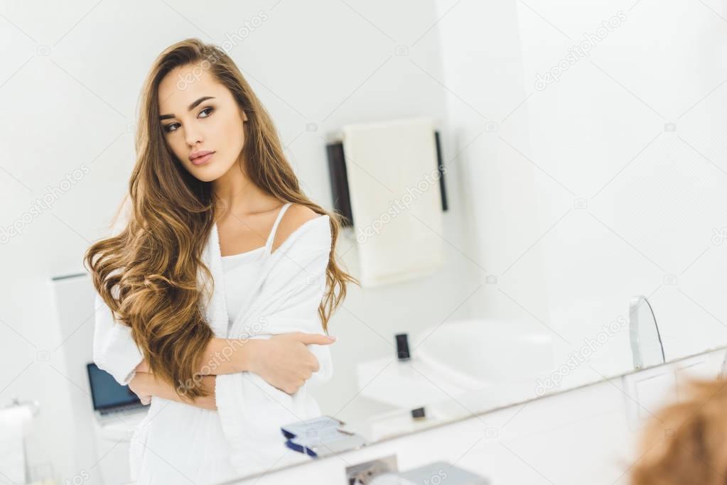 mirror reflection of attractive young woman in bathroom