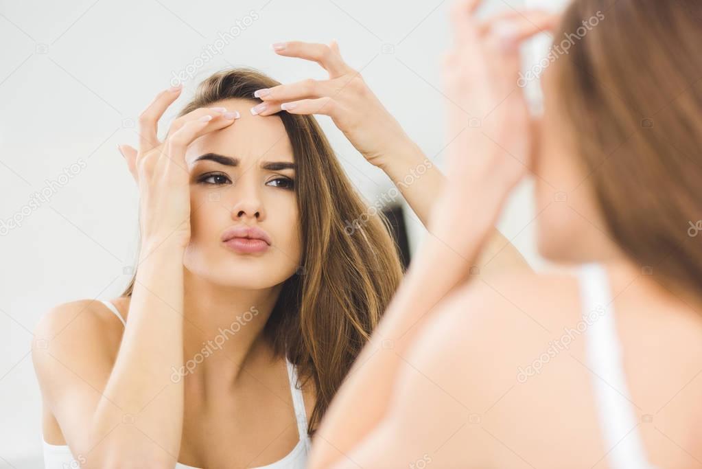 portrait of beautiful young woman checking skin 