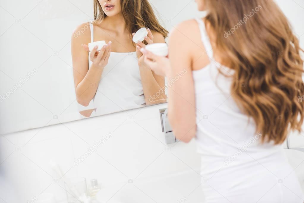 cropped shot of woman holding face cream in hands