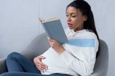 Afro-Amerikan hamile kadın evde kitap okuma