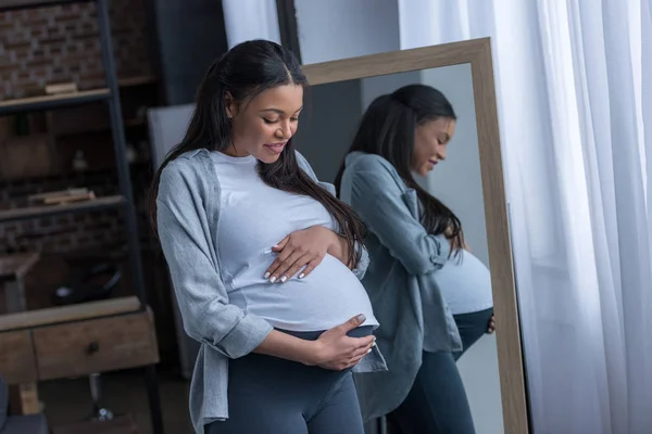 Mulher Grávida Afro Americana Olhando Para Barriga Enquanto Está Espelho — Fotografia de Stock