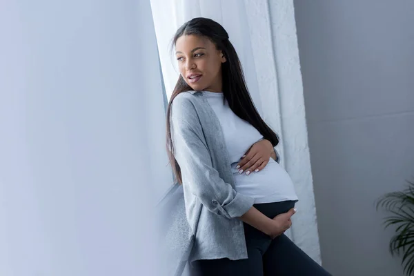 Bela Mulher Grávida Afro Americana Tocando Sua Barriga Enquanto Olha — Fotografia de Stock Grátis