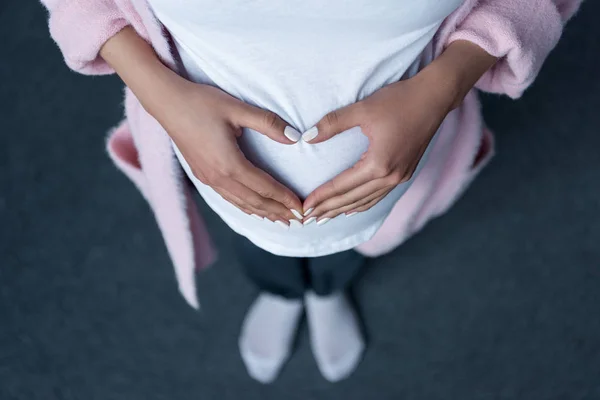 Visão Cortada Menina Grávida Fazendo Símbolo Coração Com Mãos Sua — Fotografia de Stock