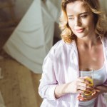 Ελκυστική γυναίκα στο πιτζάμες με χυμό πορτοκαλιού το πρωί