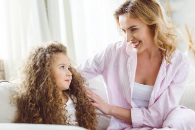 happy mother and adorable curly daughter looking at each other clipart