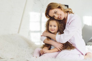 mutlu anne sevimli kıvırcık kızı kucaklayan 