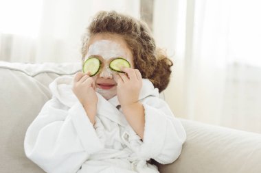 Çocuk banyo bornoz gözleri salatalık dilimleri ve yüz yüz maskesi