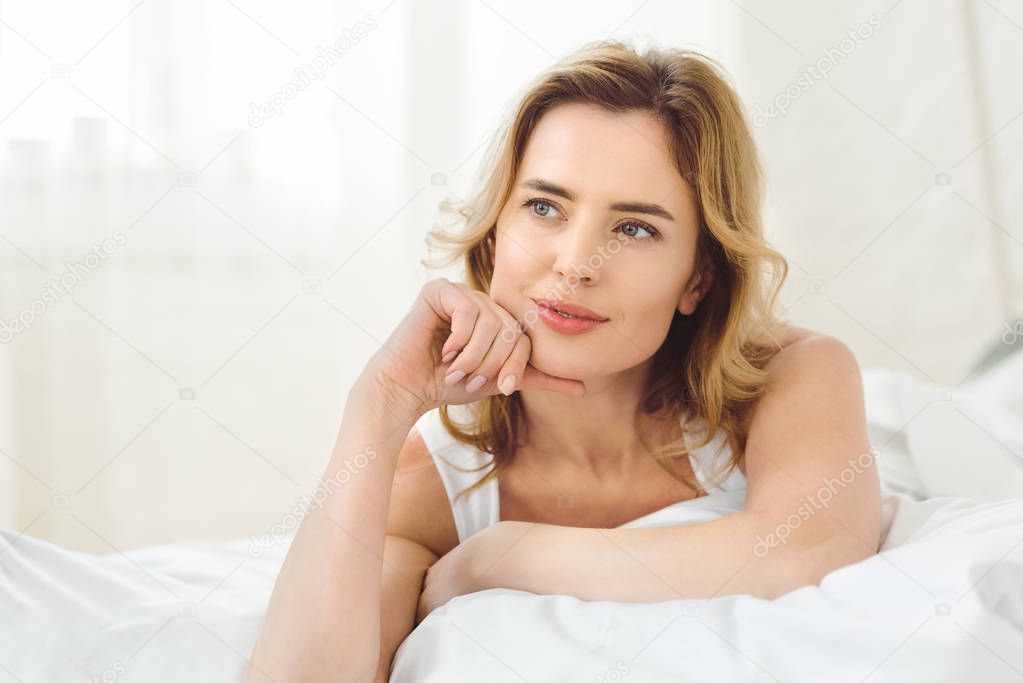 thoughtful attractive woman lying in bed at home 