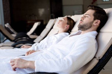 Genç çift birlikte spa merkezinde dinlenme bornoz yan görünüm