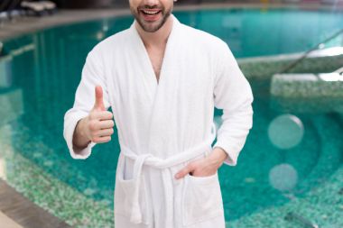 spa merkezinde başparmak gösterilmesini bornoz genç adam gülümseyen in atış kırpılmış