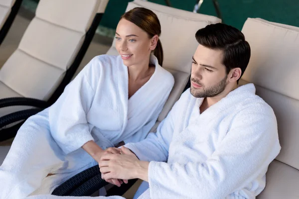 Feliz Pareja Joven Albornoces Tomados Mano Mirando Hacia Otro Lado — Foto de Stock