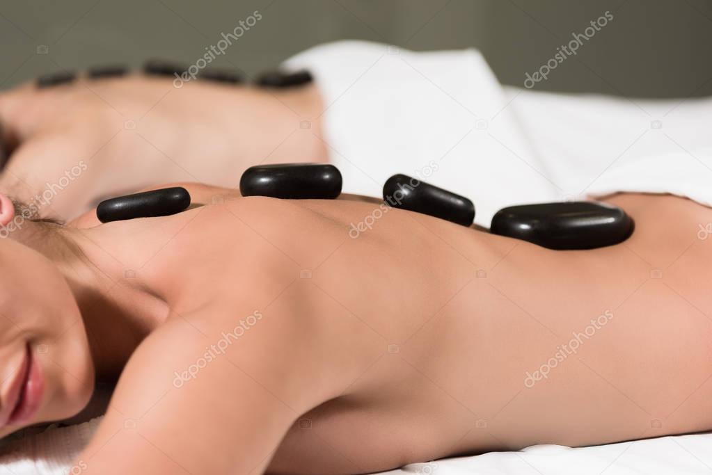 cropped shot of couple receiving hot stones massage in spa center