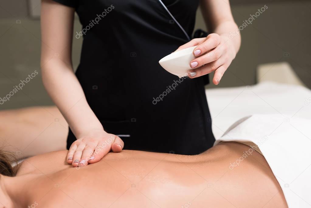 cropped shot of woman relaxing and having body massage in spa salon