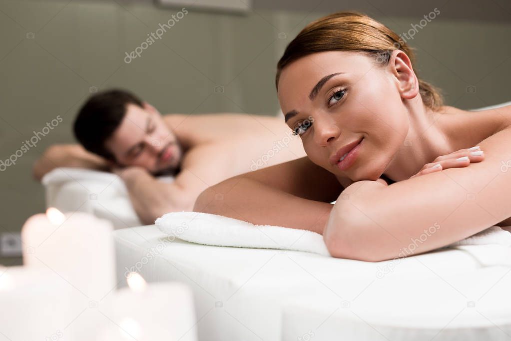 young woman smiling at camera while having massage in spa salon