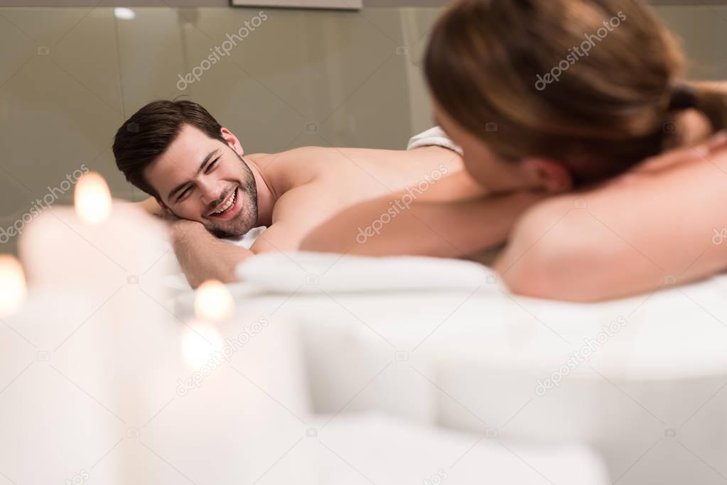 oung couple looking at each other during massage in spa salon