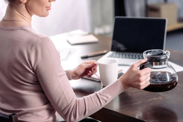 Частичный Вид Женщины Чашкой Кофе Кофеваркой Сидящей Столом Ноутбуком Дома — Бесплатное стоковое фото