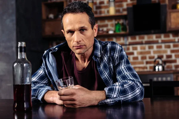 Hombre Sentado Mesa Con Botella Vaso Alcohol Casa — Foto de stock gratis