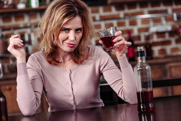 portrait of woman with glass of alcohol looking at camera at home