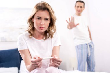 kadının gebelik testi ve arkasında üzgün kocası ile seçici odak