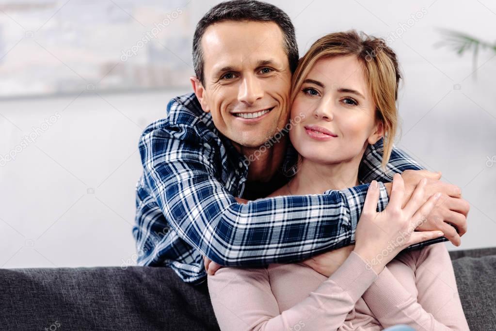 portrait of smiling couple in love looking at camera at home