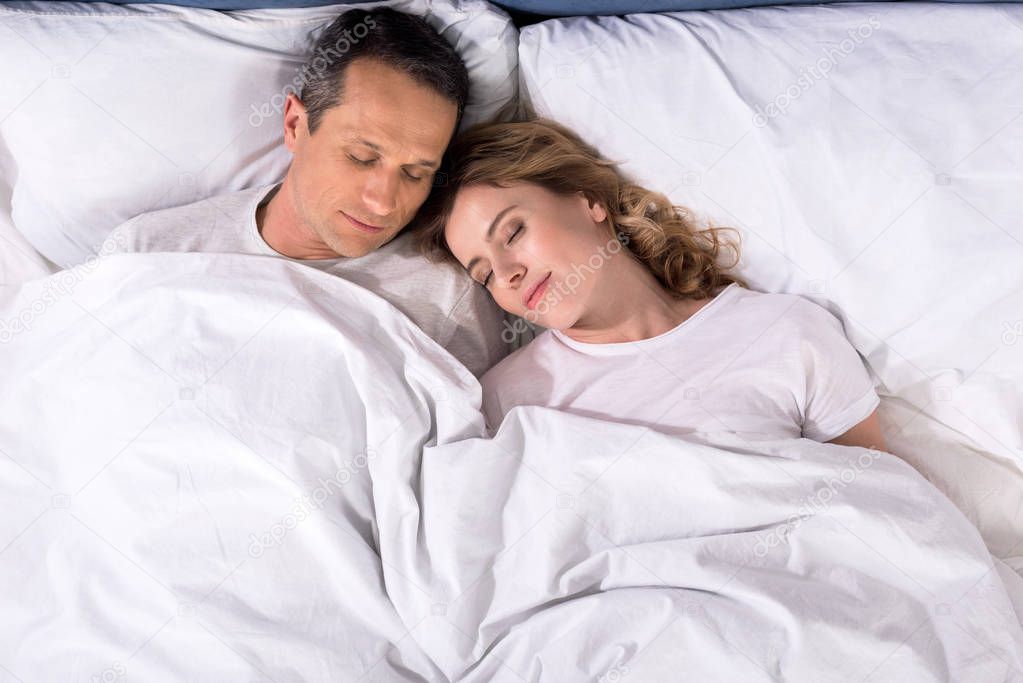 overhead view of couple sleeping in bed at home
