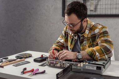 repairman using multimeter while fixing computer 