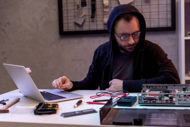 adam kırık PC'de bakarken dizüstü kullanarak hoodie