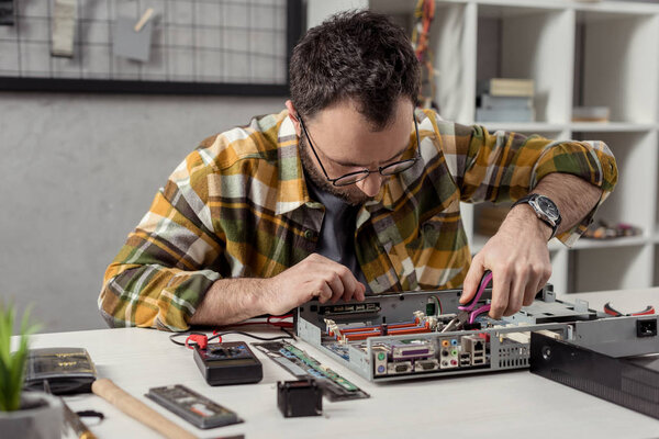 ремонтник с помощью щипцов при починке сломанного компьютера
 