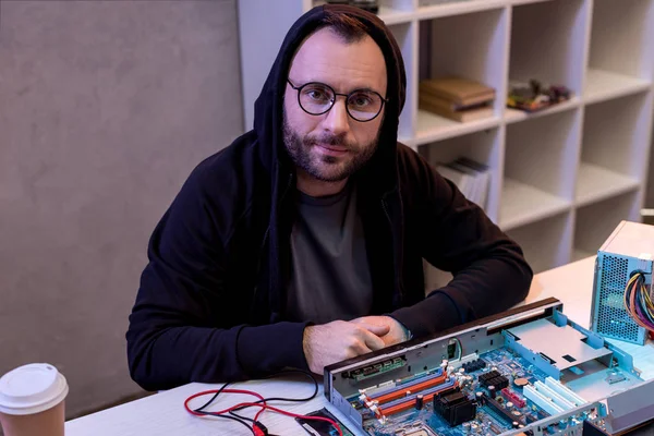 Hombre Con Capucha Sentado Contra Una Computadora Rota Mesa — Foto de stock gratuita