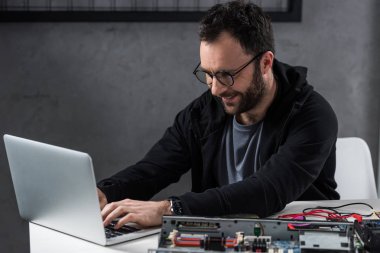 gülümseyen adam masada dizüstü kırık pc karşı kullanma