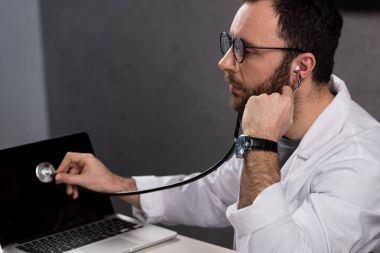 male doctor in white coat and stethoscope diagnose laptop  