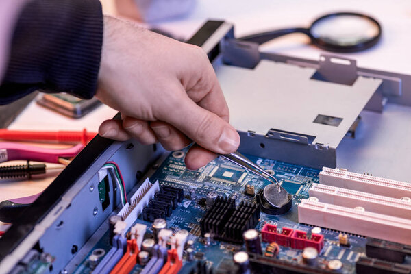 cropped image of repairman fixing motherboard