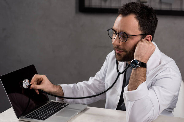repairman in doctor white coat using stethoscope to diagnose laptop 
