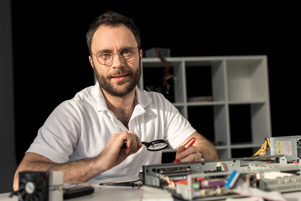 man in glasses looking at camera while he fixing pc