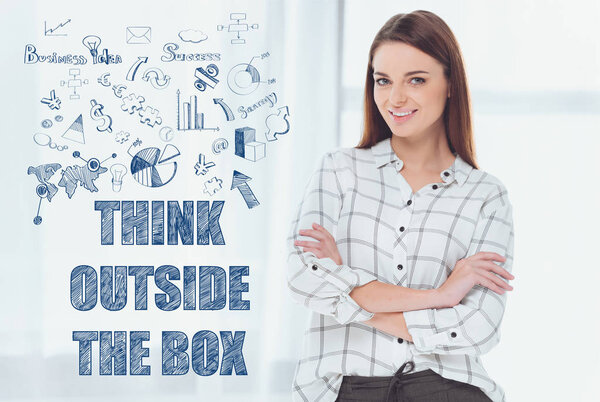 привлекательная деловая женщина, стоящая со скрещенными руками и смотрящая в камеру, надпись мыслит нестандартно
