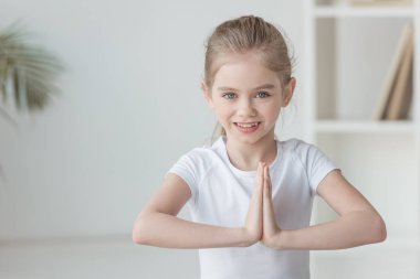 küçük çocuk pratik yoga gülümseyen ve namaste hareketi yapma