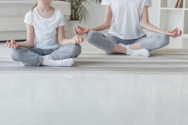 Anne ve kızı lotus meditasyon kırpılmış görüntüsünü birlikte evde poz