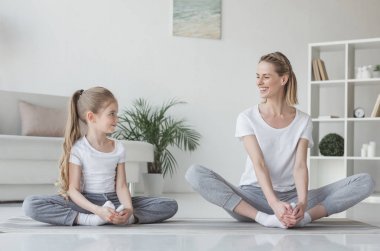 Anne ve kızı pratik yoga kelebek içinde evde poz
