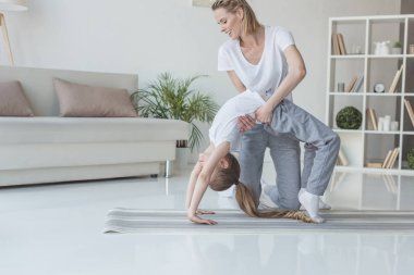 mutlu anne kızını evde Yoga tekerlek poz durmak için öğretim