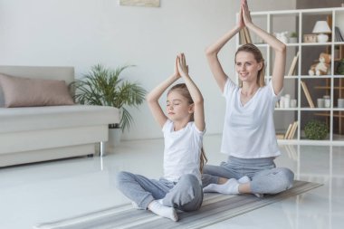 Anne ve kızı pratik yoga lotus içinde evde poz