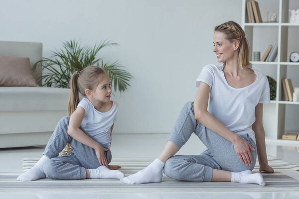 мать и дочь практикуют йогу вместе в позе Маричи
