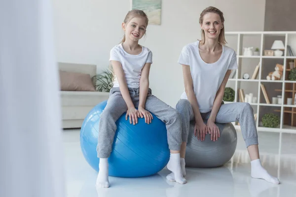 微笑的母亲和女儿坐在适合的球在家里 — 免费的图库照片