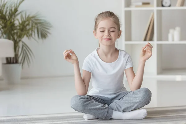 Smiling little child meditating in lotus pose at home — Stock Image Smiling Little Child Meditating Lotus Pose Home Stock Photo