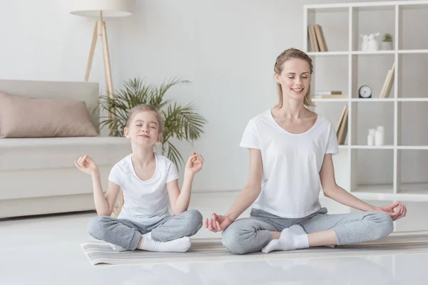Mother and daughter sitting in lotus pose at home and meditating together — Stock Image Mother Daughter Sitting Lotus Pose Home Meditating Together Stock Picture