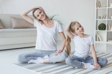 Anne ve kızı evde egzersiz öncesine boyun germe